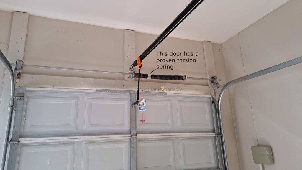 An image of an 8x8 garage metal garage door that has a broken torsion spring.